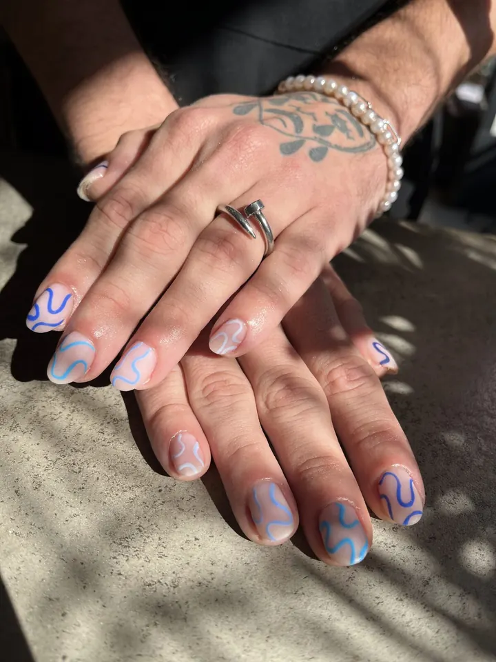 Manicura nude con líneas onduladas en azul
