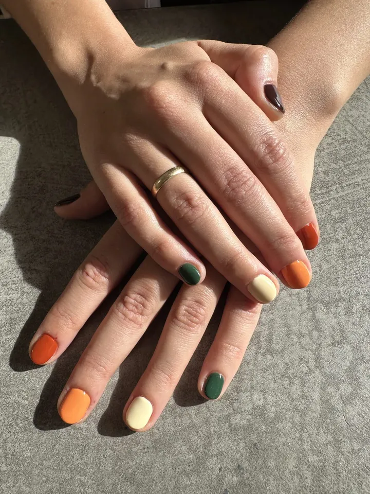 Uñas cortas en colores de otoño: naranja, crema, verde oscuro y marrón